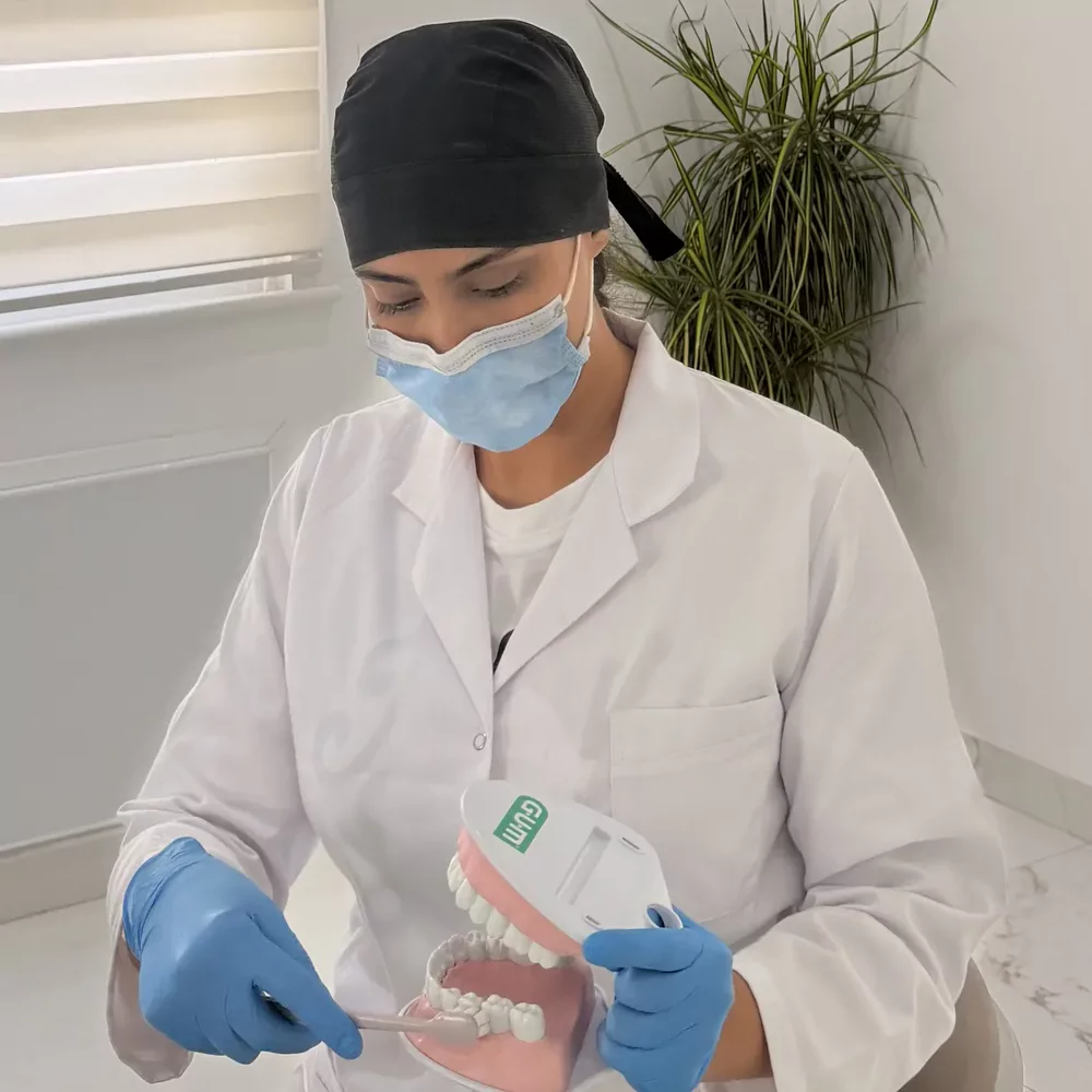 Dr Majda Laasraoui montrant le brossage sur un modèle de mâchoire, en salle de soins